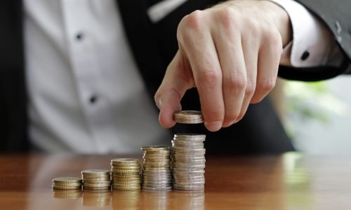 closeup-shot-businessman-s-hands-counting-stacks-coins-after-business-success